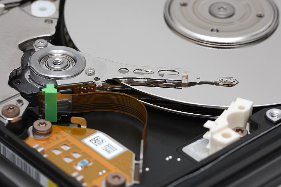 Interior of an open hard disk drive showing the magnetic platter and read/write head on its actuator arm