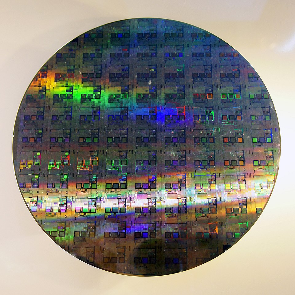 A 12-inch silicon wafer showing dozens of processor dies arranged in a grid across its mirror-smooth surface